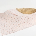 Pink muslin swaddle blanket with white cartoon rabbits and carrots on a woven basket - Cute Rabbit