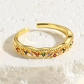 Close-up of golden adjustable ring with wavy texture and colorful zircon stones on stone - Wave Multicolor Zirconia