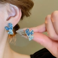 Détail de boucles d'oreilles fleurs en émail bleu aux bords dorés portées par un mannequin - Émail Coeur Irrégulier (2#)