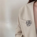 Elegante spilla a camelia nera traforata con cristalli sul risvolto di un cappotto beige - Camelia in Strass Nero