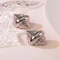 Macro detail of silver croissant earrings with glossy mirror finish on textured surface - Croissant
