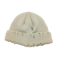 Détail du bonnet en maille blanc cassé avec épingle de sûreté punk et anneaux argentés - Beige