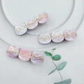 Macro view of purple and pink marble textured acetate cat hair clips on a white plate - Shiny Purple