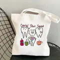 White canvas tote bag with Dental Stain Squad print resting on a black wire chair - C7 Dental Stain Squad
