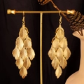 Nahaufnahme der goldenen mehrschichtigen Blattohrhänger an einem Ständer mit Pinienzapfen - Kleines Blatt / Gold