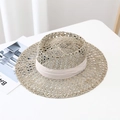 Detail of hand-woven seagrass sun hat with elegant beige ribbon on a minimal white surface - M / Beige