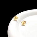 Macro detail of golden flower stud earrings on white ceramic edge with high-gloss finish - Gold Hollow Flower Cartilage Stud (Single)