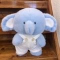 Zachte lichtblauwe olifant knuffel met wit gestreepte tuinbroek op houten trap - Olifant in Witte Tuinbroek / Witte Tuinbroek Stijl