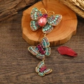 Golden butterfly brooch with multi-colored rhinestones on rustic wood background - Colorful