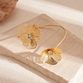 Detail of gold floral open bangle with hollow wire petals and sparkling white zircon center - Gold Flower