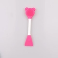 Detailed macro view of a pink dual-sided silicone face brush with bear-shaped bristles - Rose Red