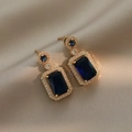 Elegant gold earrings featuring blue rectangular gemstones surrounded by small crystals - Blue Gemstone Earrings