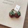 Detail of two handmade knitted strawberry hair ties with green leaves and yellow seeds - Brown Strawberry