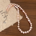 Detailed close-up of natural freshwater pearl necklace with S925 silver clasp on wood - Colored Freshwater Pearl Necklace