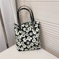 Dettaglio borsa tote vintage floreale con spalline in pelle nera e borchie dorate - Sfondo Nero Grandi Fiori Verde Bianco