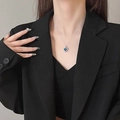 Silver heart necklace featuring a deep blue sapphire pendant on a female model - Blue Ocean Heart / Blue Silver Chain