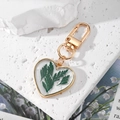 Portachiavi a cuore in resina con veri fiori secchi e cornice dorata su marmo bianco - Foglia Verde