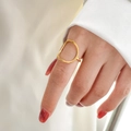 Dettaglio di un anello geometrico dorato minimalista indossato al dito per un look chic - US 7 / Grande cerchio traforato