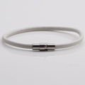 Detail of white leather cord bracelet with silver magnetic buckle on light background - White