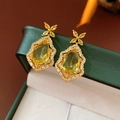 Detailed macro view of golden teardrop earrings with crystals and clover design - Gold