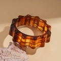 Detailed macro view of the amber resin bangle featuring wavy edges and tortoiseshell texture - Light Coffee