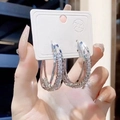 Close-up of silver multilayer hoop earrings with sparkling white crystals held by a hand - Silver with White Zirconia