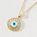 Macro detail of gold evil eye pendant featuring white zircon inlay and blue enamel center - Style A-Gold Disc Zirconia Eye