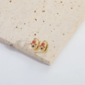 Goldene Hamsa-Hand-Ohrringe mit bösem Blick und Zirkon auf Steinoberfläche - Rot