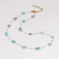 Detailed macro view of a gold chain necklace with green stones and small white pearls - Necklace
