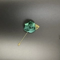Close-up of handmade emerald green satin rose lapel pin with golden leaf and long metal needle - Dark Green