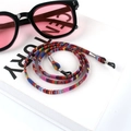 Detail of bohemian colorful braided cotton eyewear strap coiled on white prop - US 12