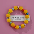 Ceramic beaded bracelet with large yellow star and colorful round beads on pink background - Yellow Star Color Round (1586-13)