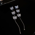 Makro-Detail von Silber-Quastenohrringen mit Zirkon-Schmetterling auf schwarzer Fläche - Silberne Schmetterlings-Zirkonia-Dreifachquaste (925 Sterling Silver Earring Post)