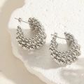 Close-up of silver C-shaped bead earrings on a textured stone tray with side lighting - CCB Beads-Silver