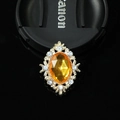 Dettaglio macro di spilla vintage con zircone arancione e montatura in lega dorata - Gemma Gialla