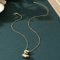 Detail view of 3D balloon style letter E pendant with beaded gold necklace chain - Letter E