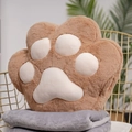 Brown cat paw plush pillow in soft material placed on a grey blanket and golden chair - Coffee