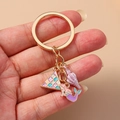 Golden mermaid and seashell keychain with colorful enamel charms held in hand - Mermaid