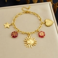 Bracciale dorato con ciondoli a sole, cuore, stella e fiori rossi su portagioie - Bracciale con Disco Solare a Più Pendenti (B1836)