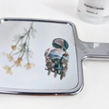 Mini acetate hair claw clip with blue and white marble pattern shown on a mirror surface - Magic Green