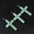 Green aventurine crystal cross pendant with silver bail on textured black background - Green Aventurine