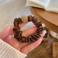Brown satin scrunchie featuring a golden rhinestone ball charm in a hand-held close-up - Satin Rhinestone Ball / Dark Coffee Rhinestone Bead