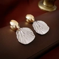 Elegant gold and silver fan-shaped shell earrings on vintage brown leather background - Silver Oval (Real Gold Plated)