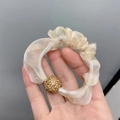 Detail of beige sheer mesh scrunchie with a sparkling gold glitter ball ornament - Organza Beige