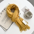 Soft mustard yellow cashmere-feel scarf with elegant fringe detail on a white desk - Turmeric