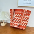 Detail of orange chevron knit tote bag with thick woven texture on a wooden table - 19 Zigzag Pattern Red