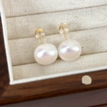 Macro shot of white freshwater pearl earrings with gold posts in a premium jewelry box - 14mm Pink Light Pearl