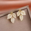 Boucles d'oreilles feuilles dorées avec cristaux étincelants sur un coffret cadeau en velours - Or