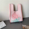 Pink knitted tote bag featuring a large rose floral pattern and green stripe accents - Light Pink