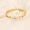 Detailansicht eines goldenen Evil-Eye-Armreifs mit blauen Edelsteinen auf Seide - Hohler Eingelegter Böser Blick Stil (6#)